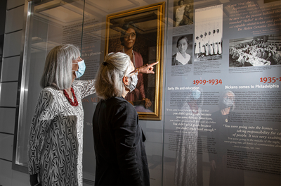 Jayne Henderson Brown, MD, and Carol Benenson Perloff look at a photo within the exhibit about Helen O. Dickens, MD